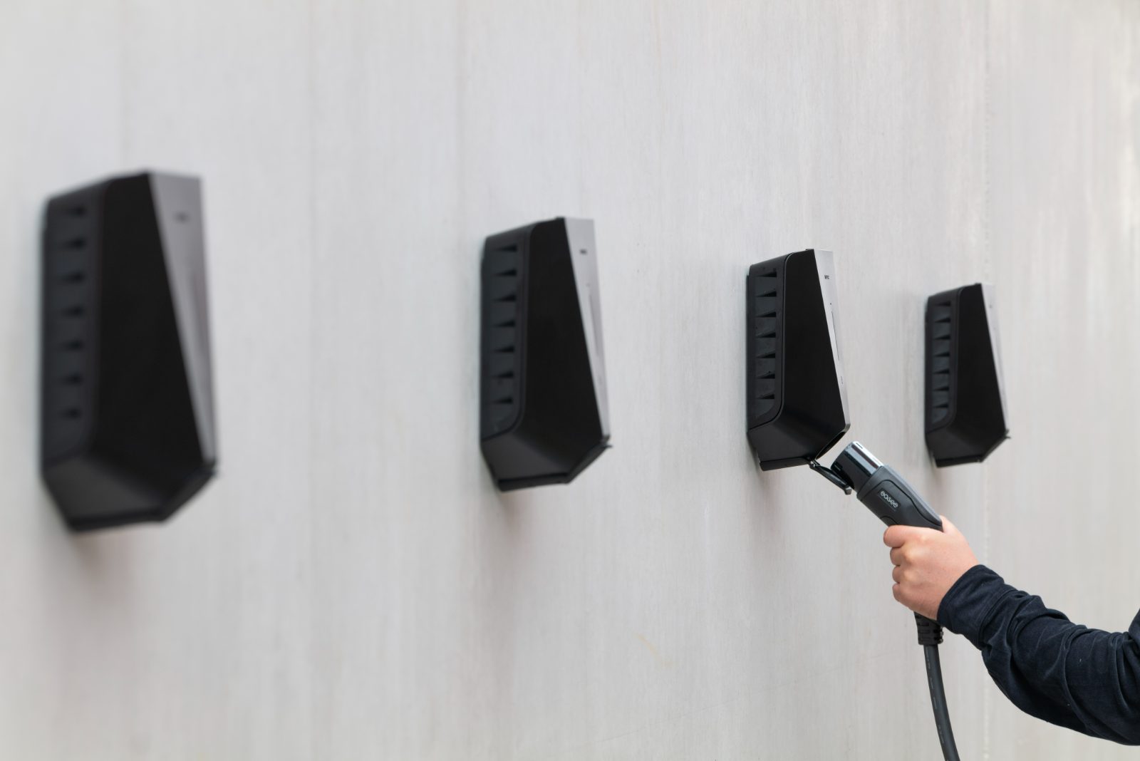 Four wall-mounted Easee chargers, one being plugged in